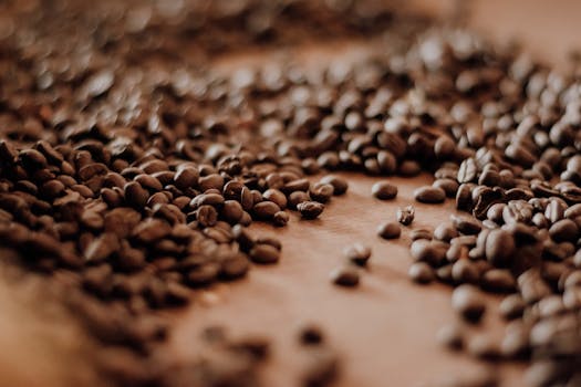Close-up of roasted coffee beans scattered on a table, highlighting texture and aroma.