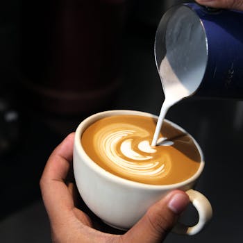 A close-up shot of latte art being poured into a cup, showcasing skilled barista technique.